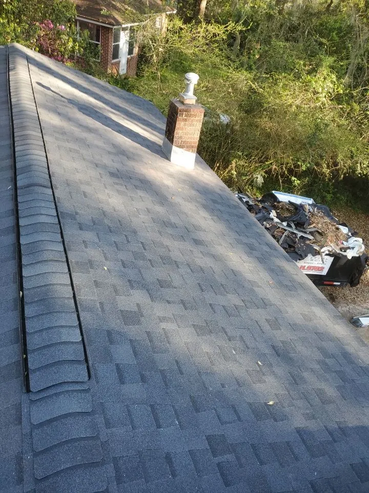 Finished ridge and architectural shingles on a Blackfoot job with the crew's truck parked below.